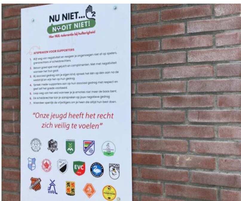 Foto van een plakkaat met gedragsregels op een muur, met daaronder allerlei clublogo's